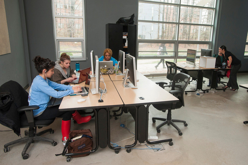 Students practice graphic design skills in a light-filled computer lab