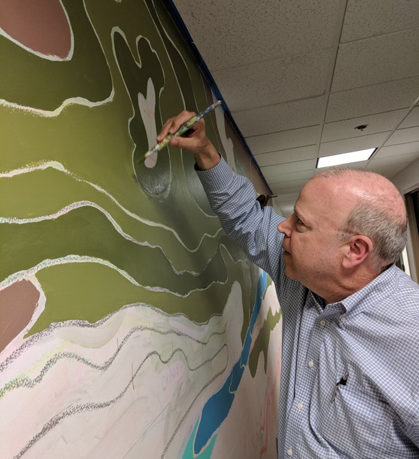 Dean Davis tries his hand at painting the mural outside his office in College Hall.