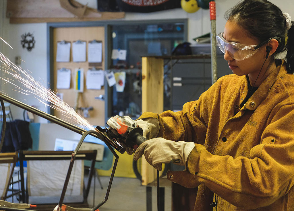 Asian woman using blow torch in the sculpture classroom at School of Art George Mason University