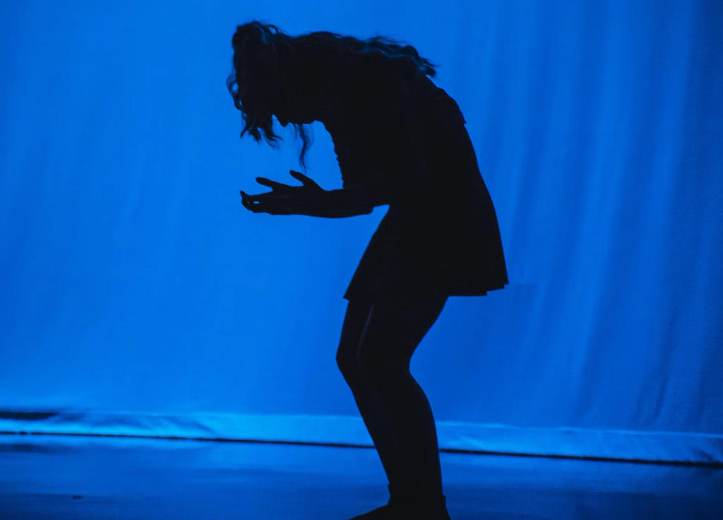 silhouetted figure on stage against blue background