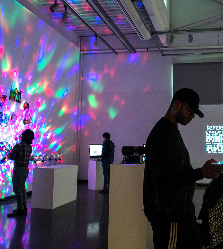 people standing looking at new media exhibition in darkened room